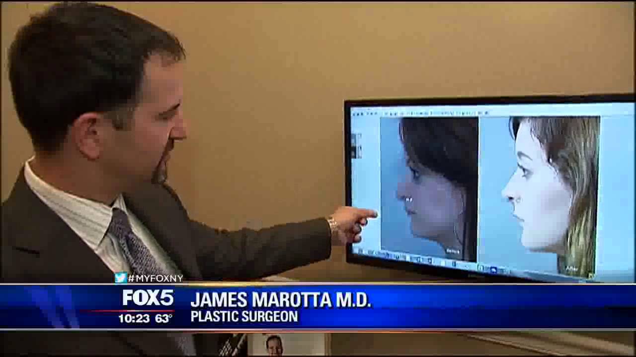 Plastic surgeon reviewing patient images on screen.