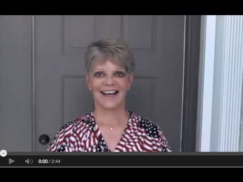 Smiling woman at a doorway video introduction.