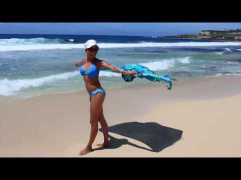 Woman dancing with scarf on a beach.