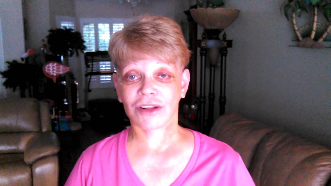 Person in pink shirt sitting indoors, smiling.