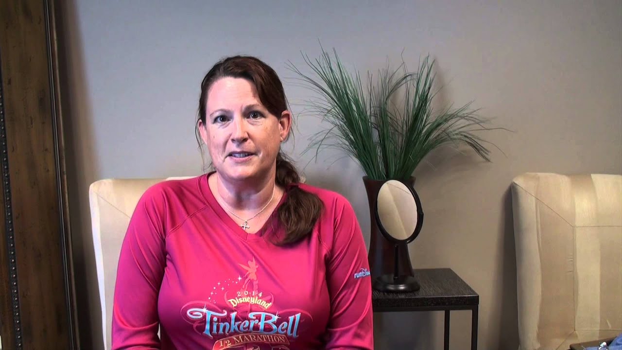 Woman in Tinker Bell marathon shirt sitting indoors.