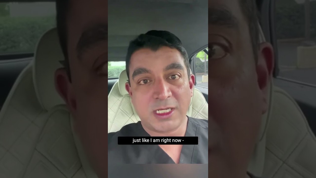Person speaking from car, wearing medical scrubs.