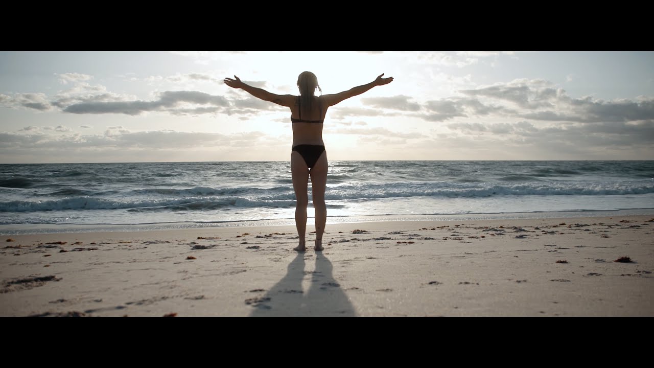 Person standing on beach with arms outstretched.