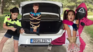 Melisa'nın kardeşini maskeli squid game askeri arabaya kilitliyor polis Melisa kurtarmaya çalışıyor.